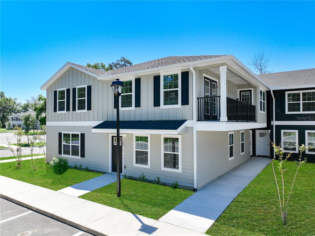 A two-story gray house with a balcony, black shutters, and a concrete walkway — 3821 SW 43RD COURT, OCALA, FL