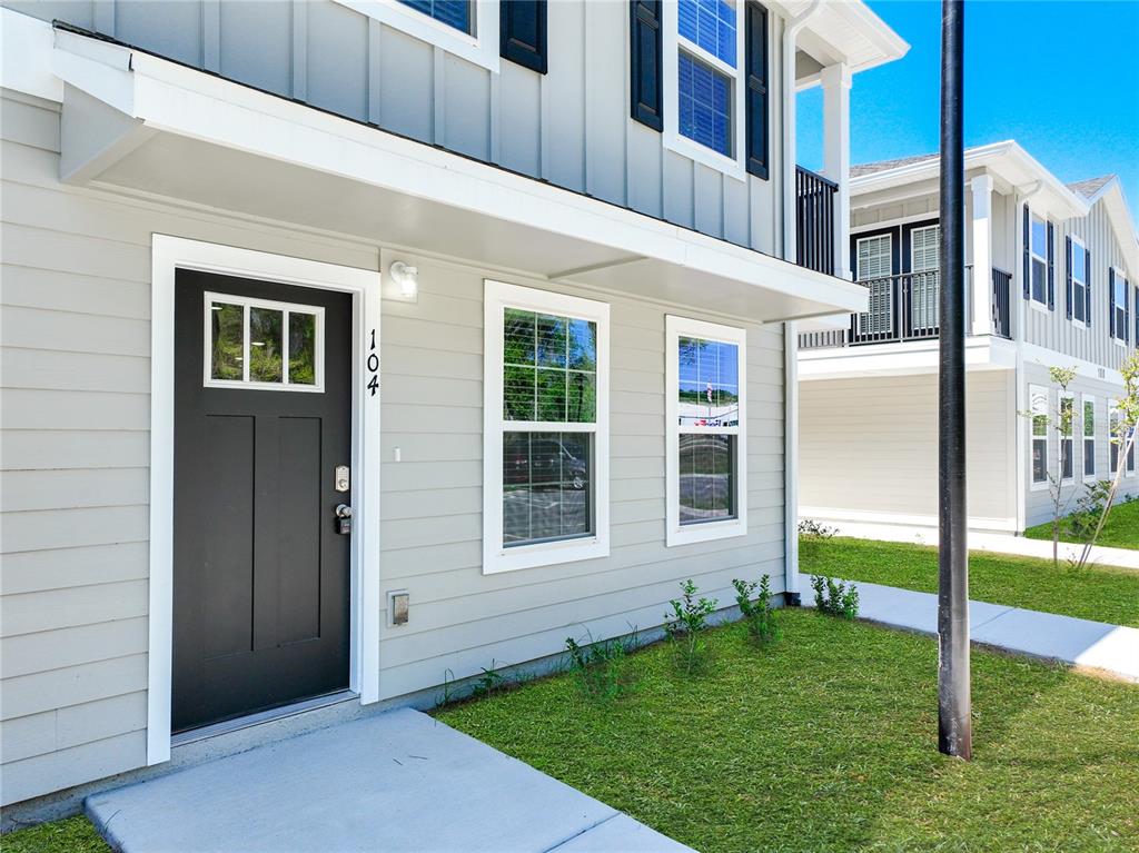 The exterior of a light gray two-story building features a black front door numbered 104 — 3821 SW 43RD COURT, OCALA, FL