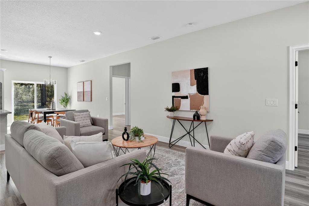 A living room features gray upholstered furniture, a round wooden coffee table, and abstract wall art — 10707 N HATARI DRIVE, CITRUS SPRINGS, FL