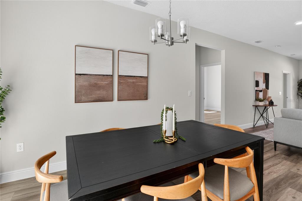 A dining room features a black table, wooden chairs, a chandelier, and wall art — 10707 N HATARI DRIVE, CITRUS SPRINGS, FL