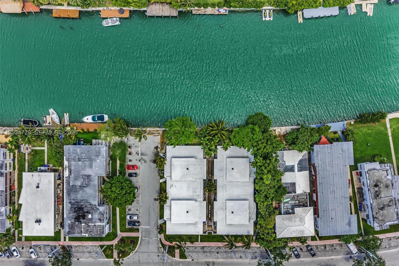 An aerial view shows several residential buildings situated along a canal with docked boats — 1795 Calais Dr, Miami Beach FL 33141, MIAMI BEACH, FL