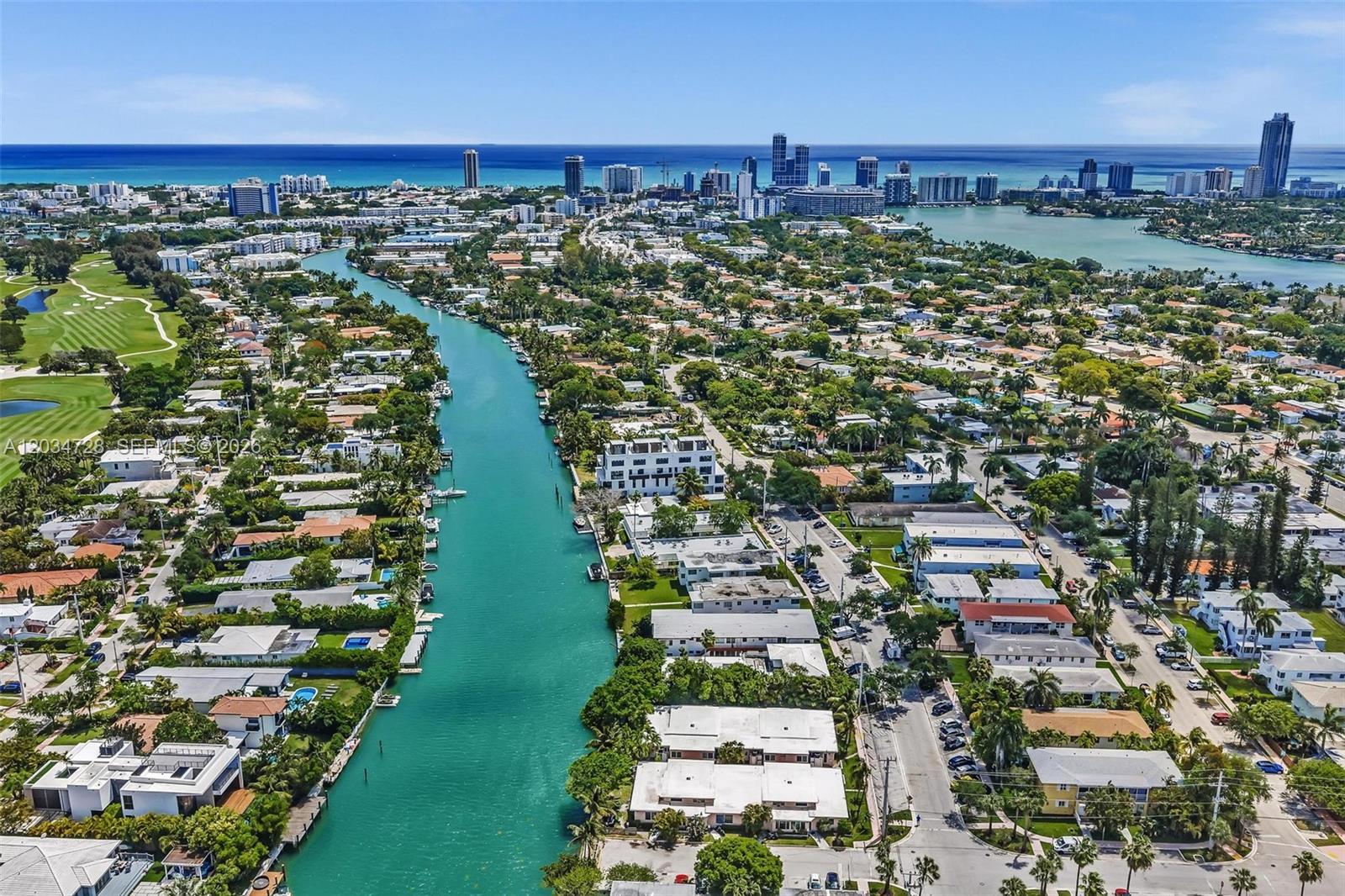 An aerial view shows a canal flowing through a residential neighborhood toward the distant ocean — 1795 Calais Dr, Miami Beach FL 33141, MIAMI BEACH, FL