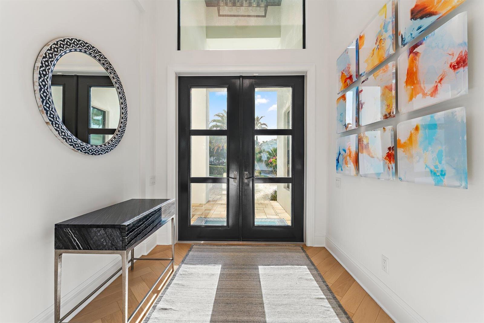 A bright entryway features a black double door, a marble console table, and abstract wall art — 17560 SE Conch Bar Avenue, Jupiter FL 33469, JUPITER, FL
