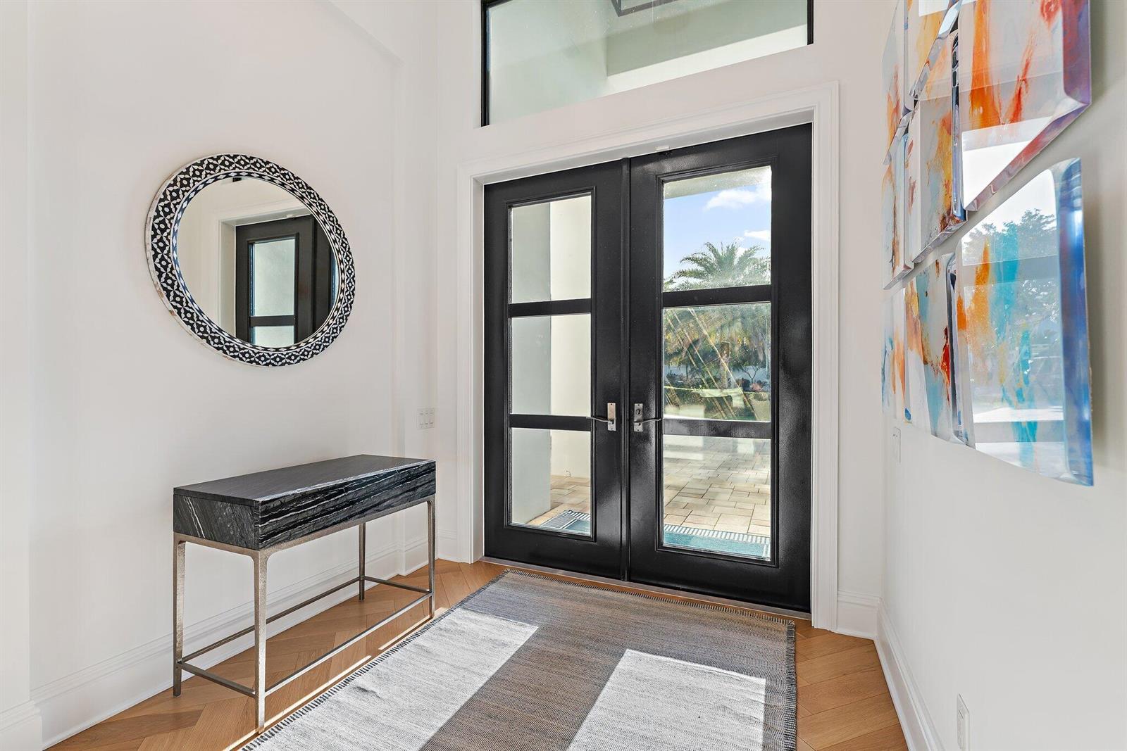 A bright entryway features a black double door, a console table, and a round mirror — 17560 SE Conch Bar Avenue, Jupiter FL 33469, JUPITER, FL