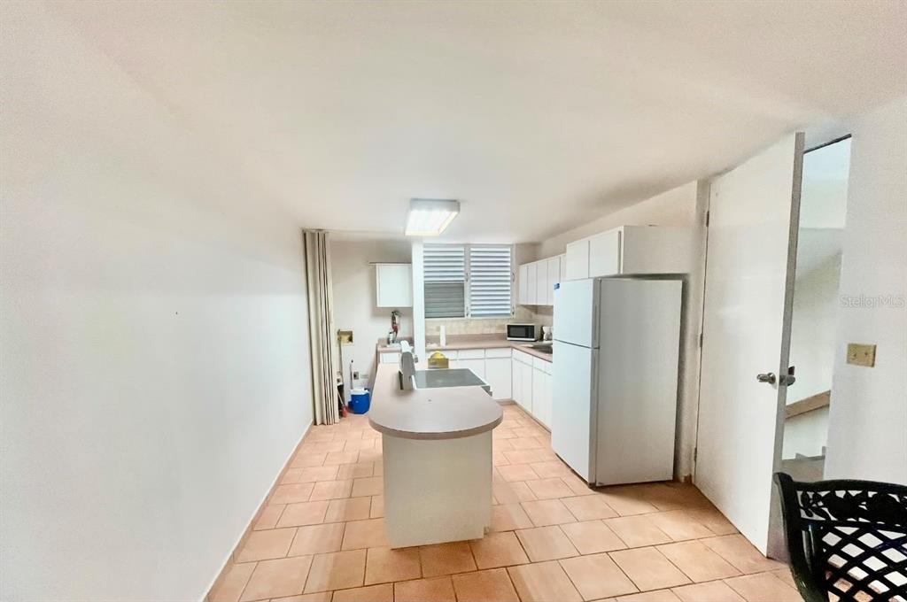 A kitchen with white cabinets, a central island, and tiled flooring — 3301 N VISTAMAR EL COMBATE UNIT 206, CABO ROJO, PR