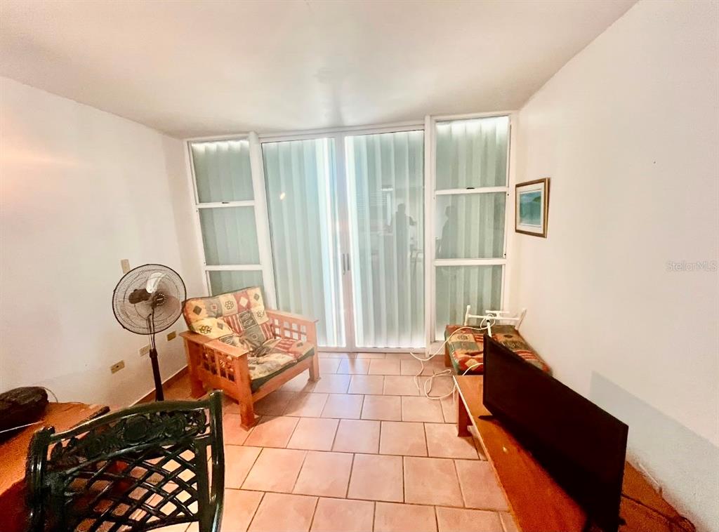 A living room features tile flooring, a wooden chair, a television, and sliding glass doors — 3301 N VISTAMAR EL COMBATE UNIT 206, CABO ROJO, PR