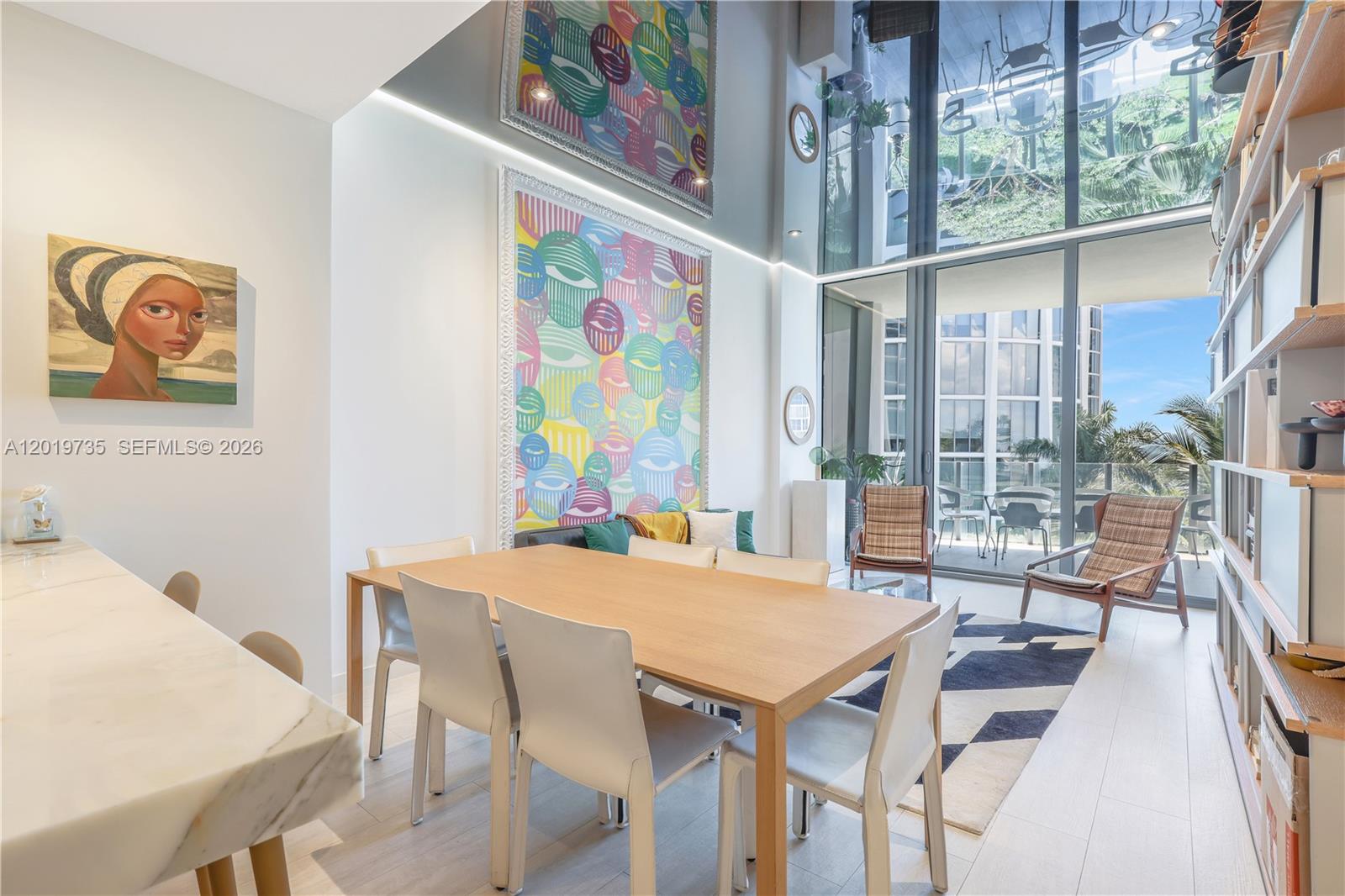 A dining area with a wooden table, modern chairs, and a large colorful wall painting — 2831 S Bayshore Dr # 603, Miami FL 33133, MIAMI, FL