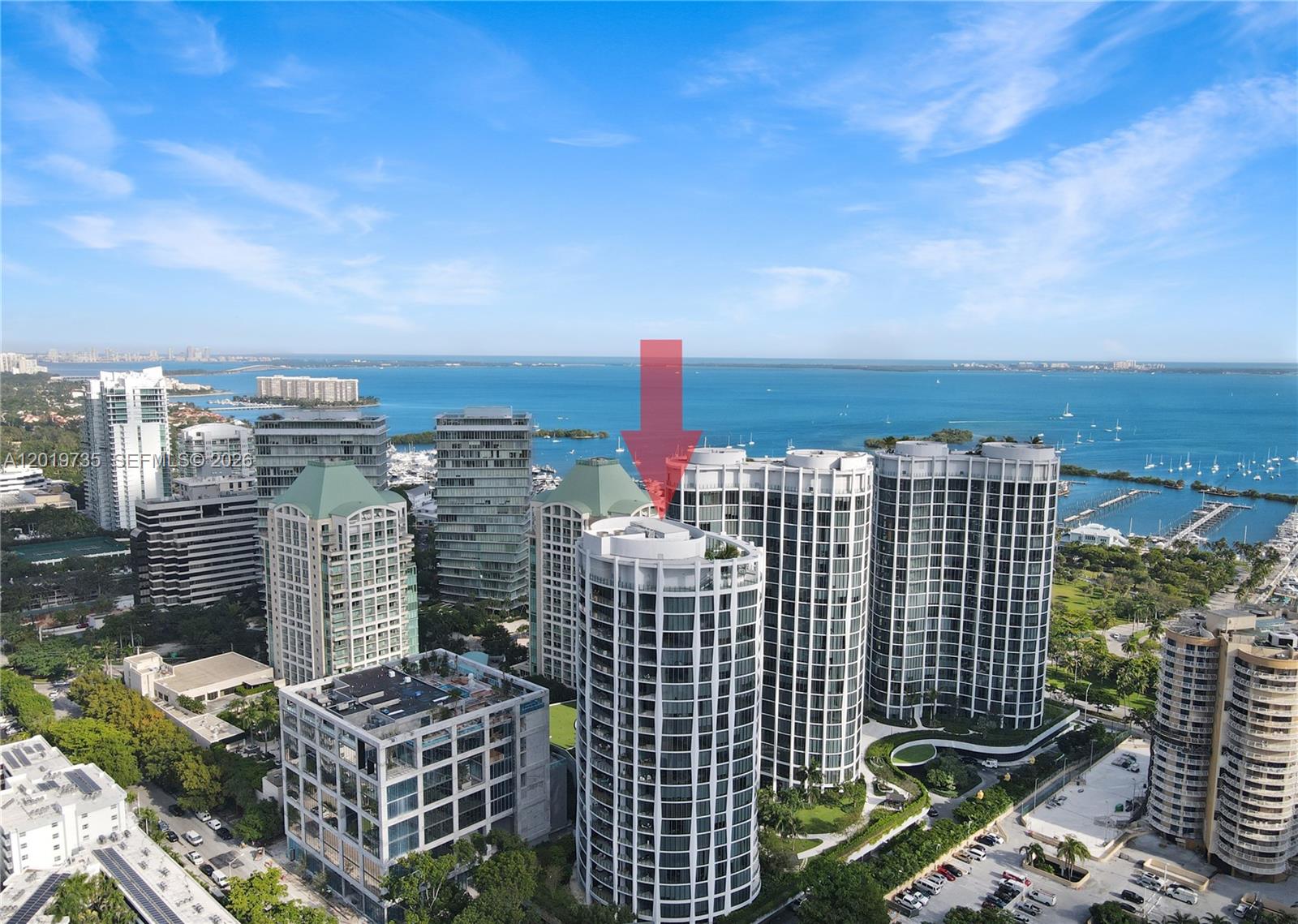 An aerial view shows several modern high-rise residential towers near a bay with boats — 2831 S Bayshore Dr # 603, Miami FL 33133, MIAMI, FL