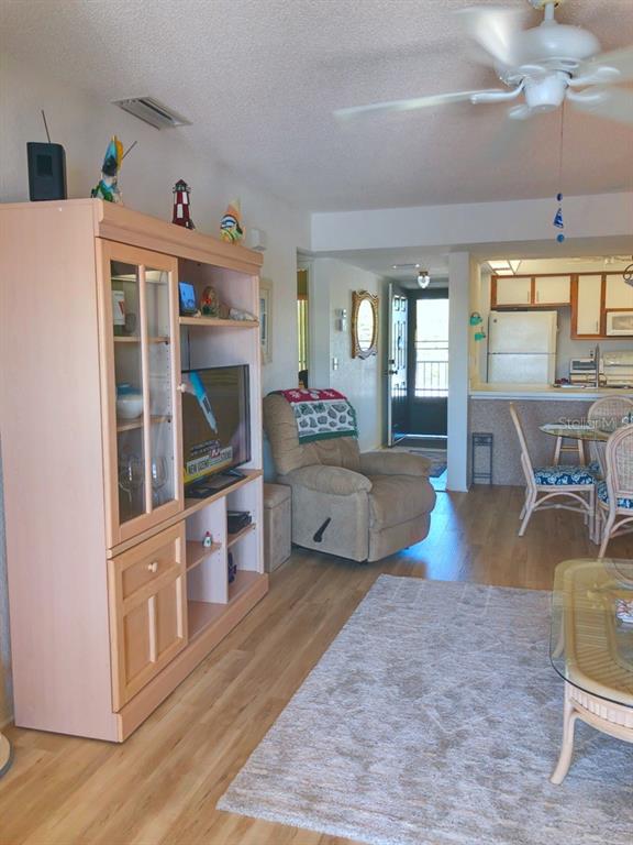 A living room with light wood flooring, a media cabinet, a recliner, and an adjacent kitchen — 4024 OAKVIEW DRIVE UNIT I9, PORT CHARLOTTE, FL