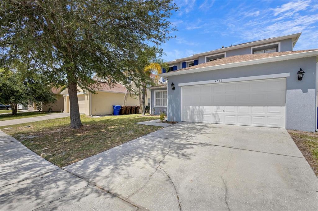 A two-story house with a light blue exterior, a white garage door, and a concrete driveway — 4539 PHILADELPHIA CIRCLE, KISSIMMEE, FL