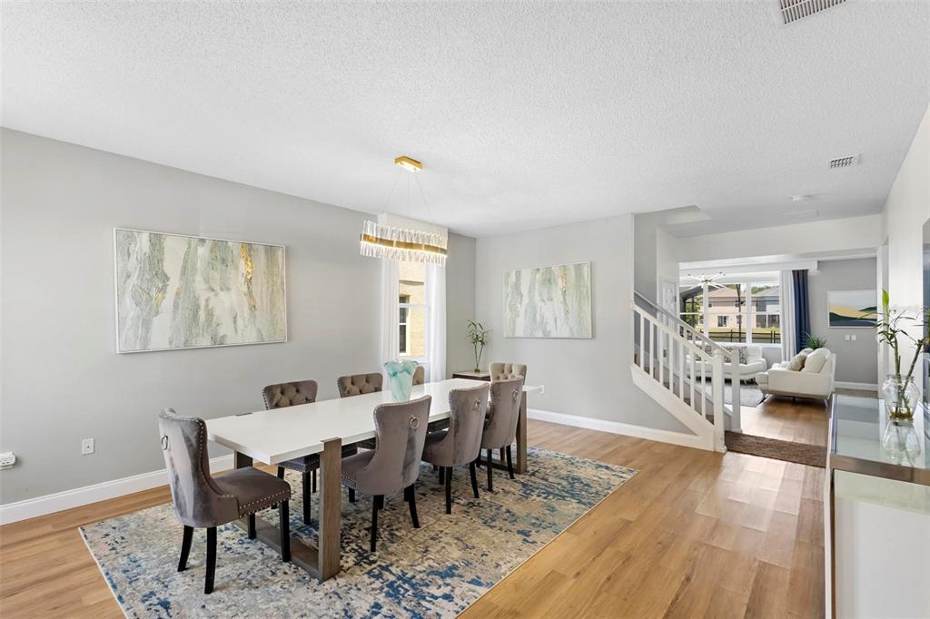 A dining room features a white table, grey upholstered chairs, and a modern chandelier — 4539 PHILADELPHIA CIRCLE, KISSIMMEE, FL