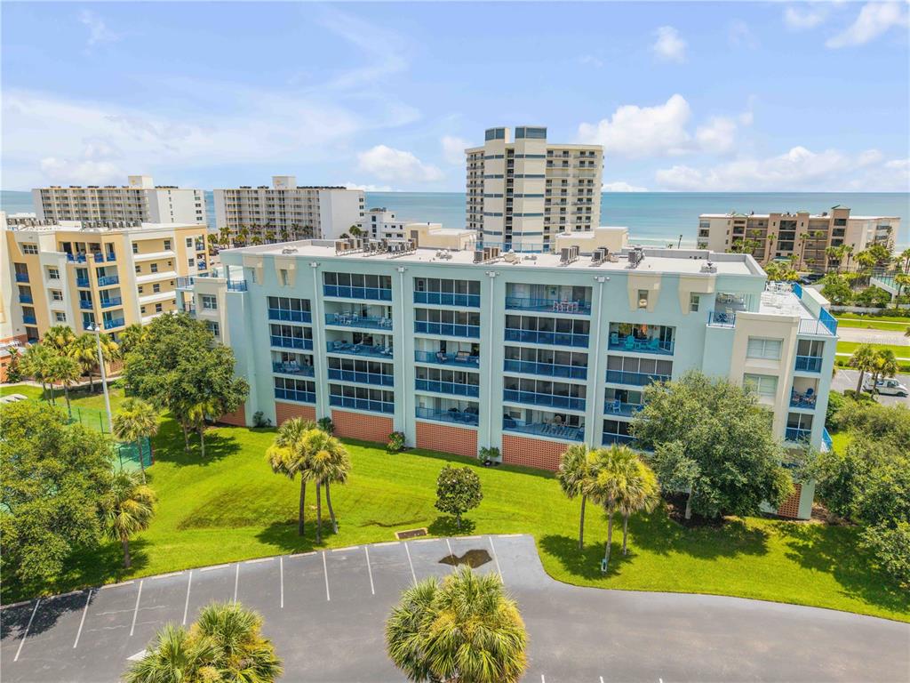 An exterior view of a multi-story light blue apartment building with balconies and a parking lot — 5300 S ATLANTIC AVENUE UNIT 1-205, NEW SMYRNA BEACH, FL