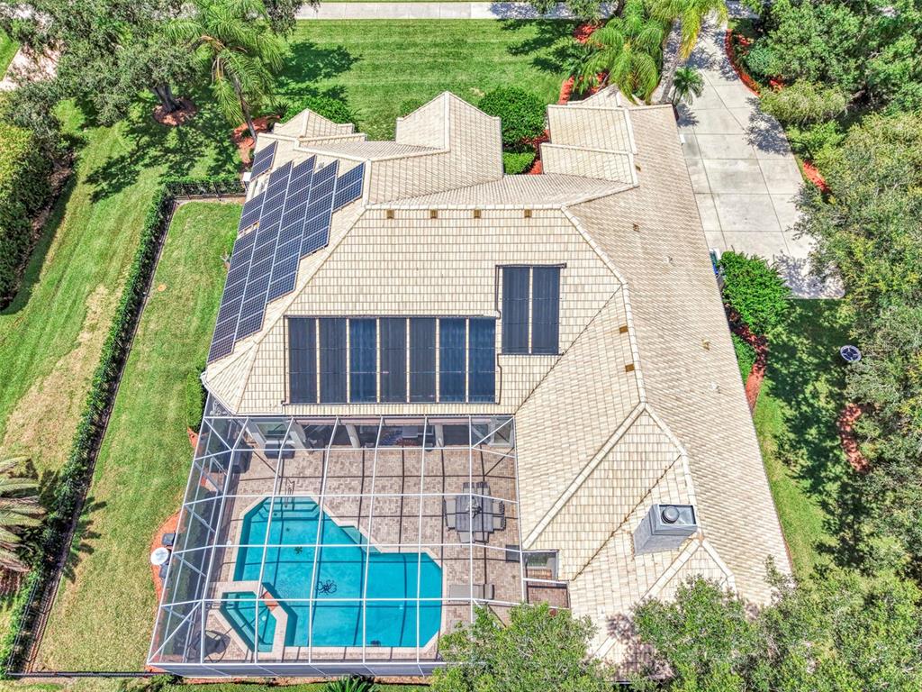 An aerial view of a house with solar panels, a pool, and a screened-in patio — 7767 ALISTER MACKENZIE DRIVE, SARASOTA, FL
