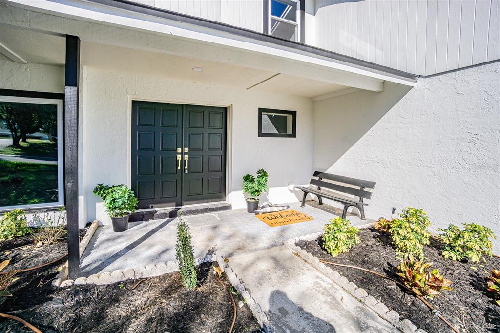 A modern kitchen features white cabinetry, marble-patterned countertops, and a large central island — 6370 CONNIEWOOD SQUARE, NEW PORT RICHEY, FL