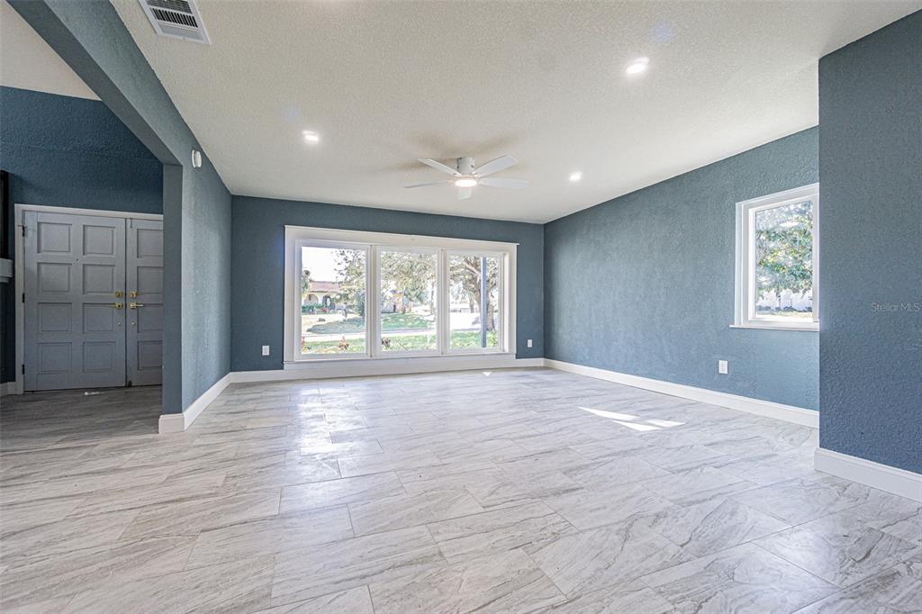 A modern kitchen features white cabinetry, marble-patterned countertops, and light-colored wood-look tile flooring — 6370 CONNIEWOOD SQUARE, NEW PORT RICHEY, FL