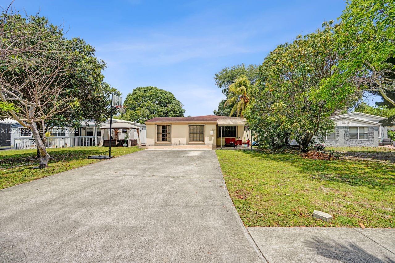 A single-story house with a concrete driveway and a large front lawn under trees — 1379 NE 177th St, North Miami Beach FL 33162, NORTH MIAMI BEACH, FL