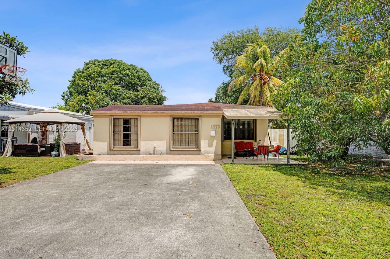 A single-story house with a concrete driveway, a front porch, and a large grassy yard — 1379 NE 177th St, North Miami Beach FL 33162, NORTH MIAMI BEACH, FL