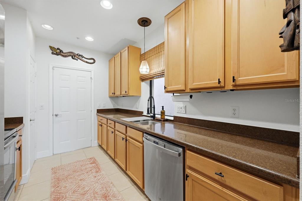 A kitchen features light wood cabinets, brown countertops, stainless steel appliances, and a tiled floor — 7210 HAMILTON ROAD, BRADENTON, FL
