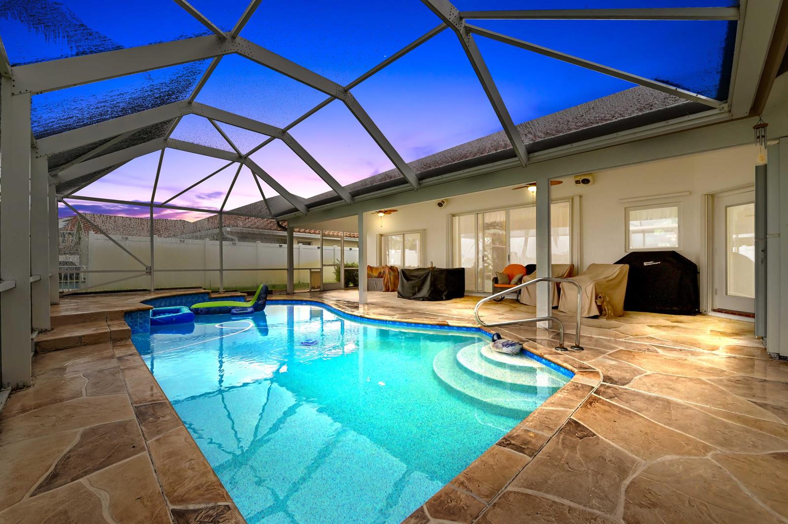 A screened-in pool patio features a stone deck, a swimming pool, and outdoor furniture — 7734 Belmont Drive, Lake Worth FL 33467, LAKE WORTH, FL