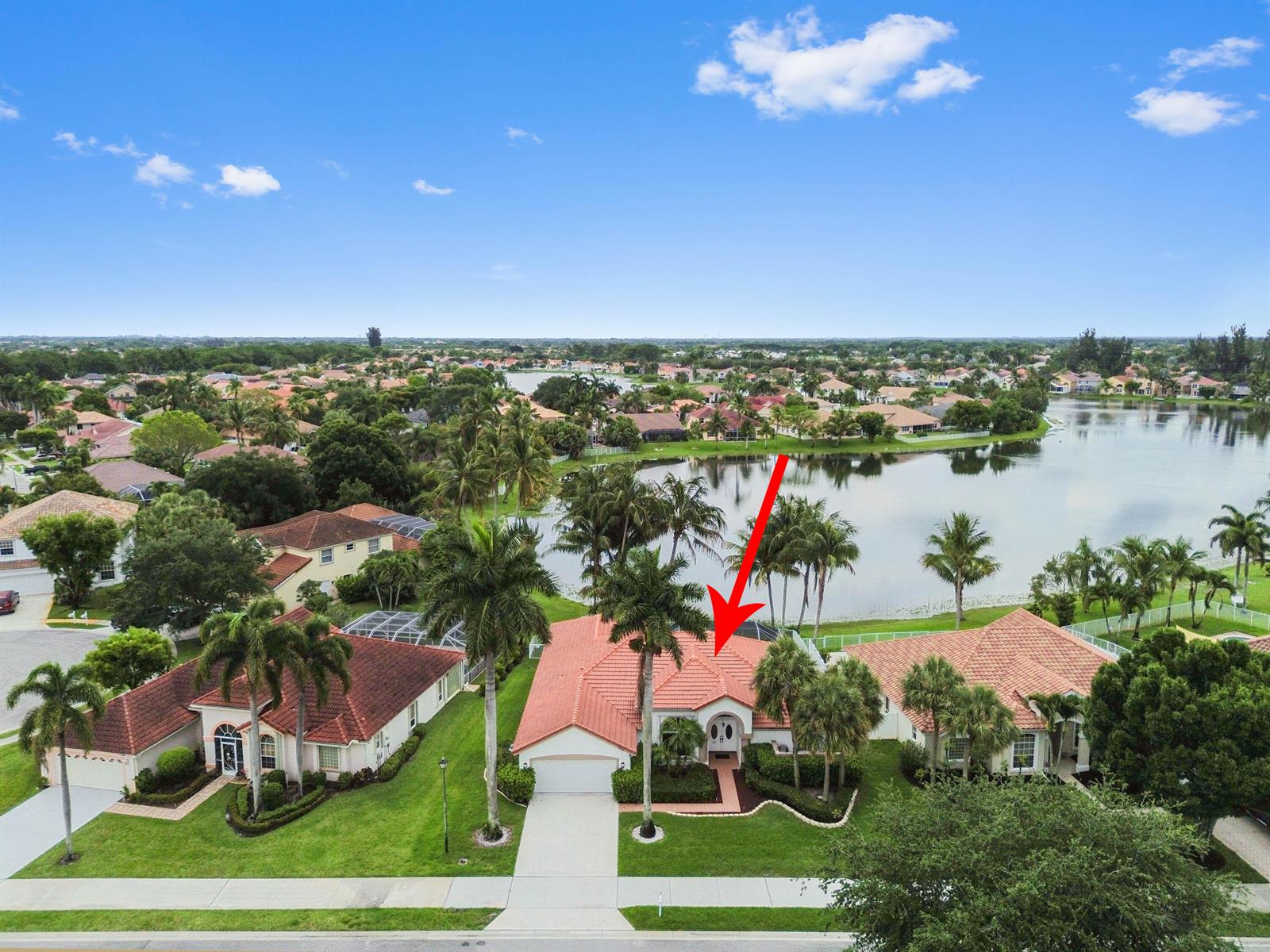 An aerial view shows a single-story house with a red tile roof near a lake — 7734 Belmont Drive, Lake Worth FL 33467, LAKE WORTH, FL