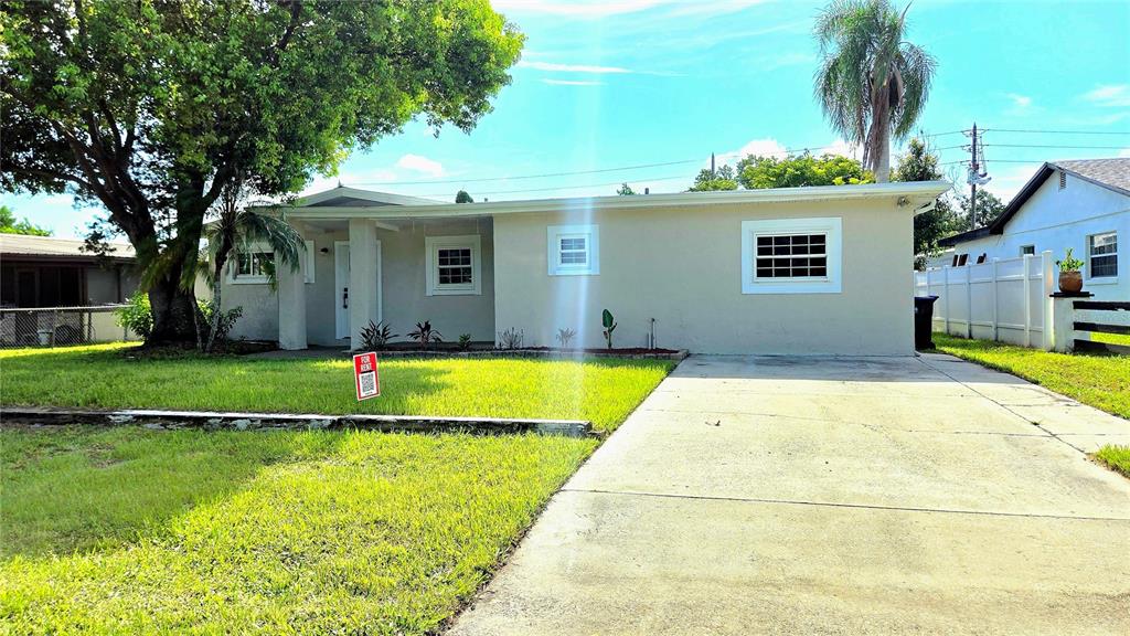 A single-story house with a beige exterior, a concrete driveway, and a large front tree — 2709 ARC DRIVE, ORLANDO, FL