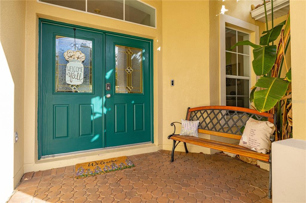 A teal double front door with a bench and a welcome mat on a porch — 1831 WINDWARD OAKS COURT, KISSIMMEE, FL