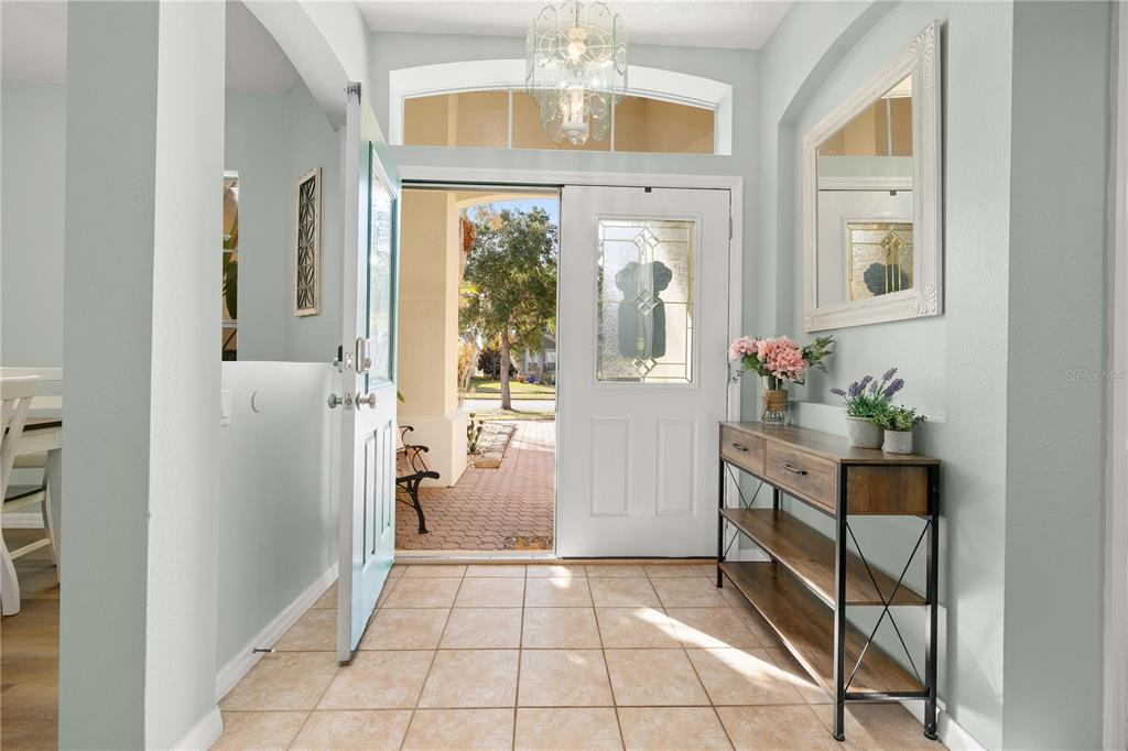An entryway features tiled floors, a light blue front door, and a wooden console table — 1831 WINDWARD OAKS COURT, KISSIMMEE, FL