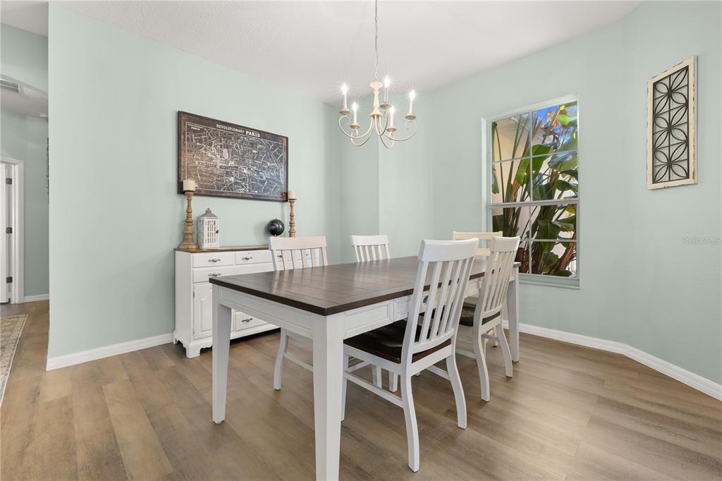 A dining room features a wooden table, white chairs, a chandelier, and light green walls — 1831 WINDWARD OAKS COURT, KISSIMMEE, FL