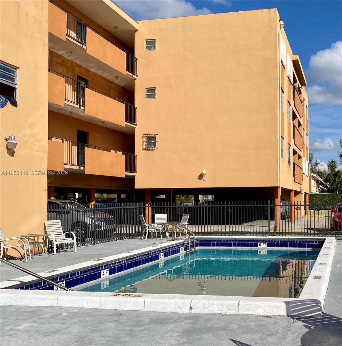 An outdoor swimming pool sits in front of a multi-story, peach-colored apartment building — 295 NW 72nd Ave # 304, Miami FL 33126, MIAMI, FL