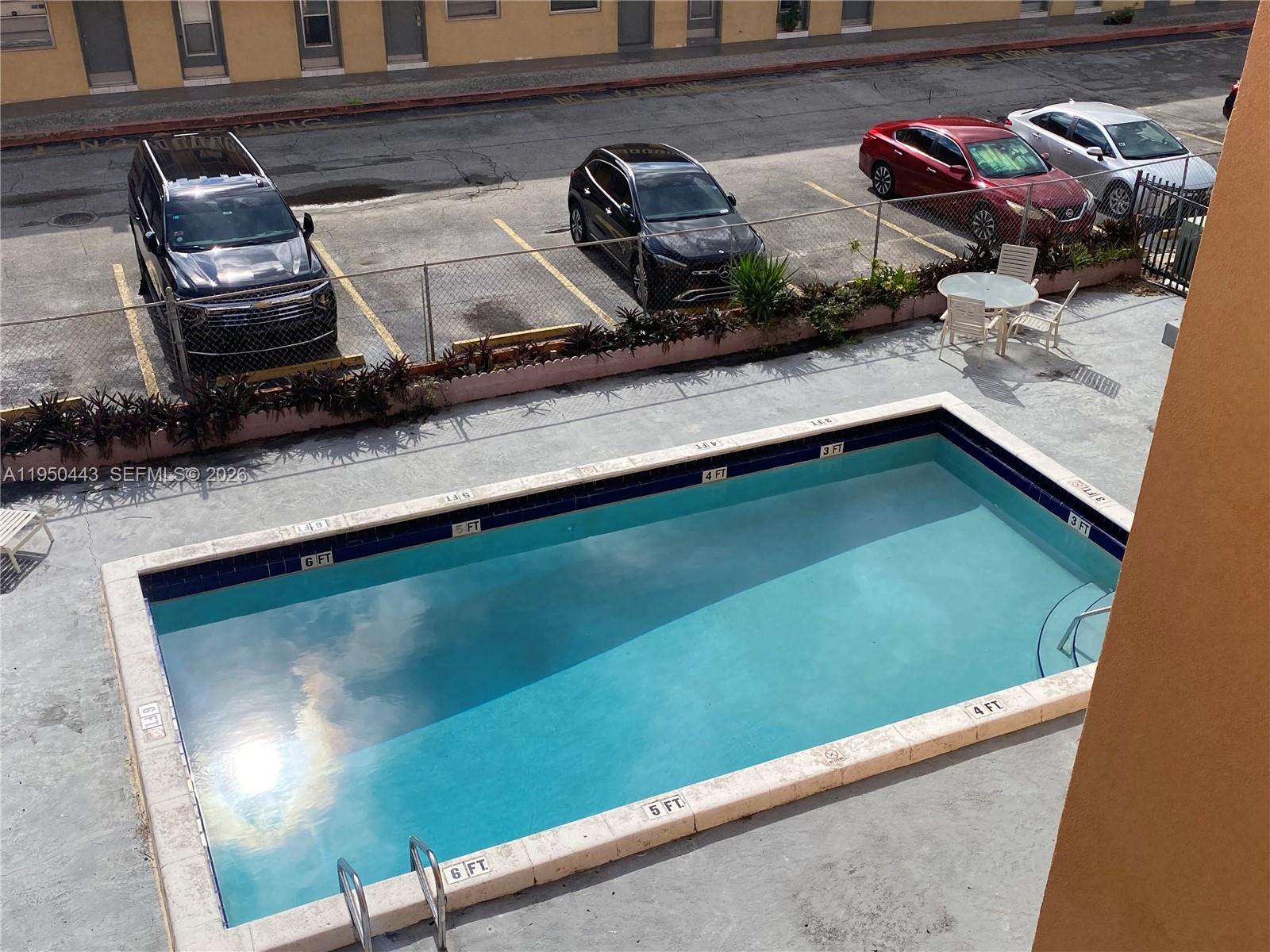 An elevated view shows a rectangular swimming pool next to a parking lot with cars — 295 NW 72nd Ave # 304, Miami FL 33126, MIAMI, FL
