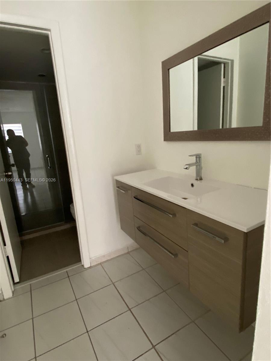 A modern bathroom features a floating vanity with a white countertop and a wall mirror — 295 NW 72nd Ave # 304, Miami FL 33126, MIAMI, FL