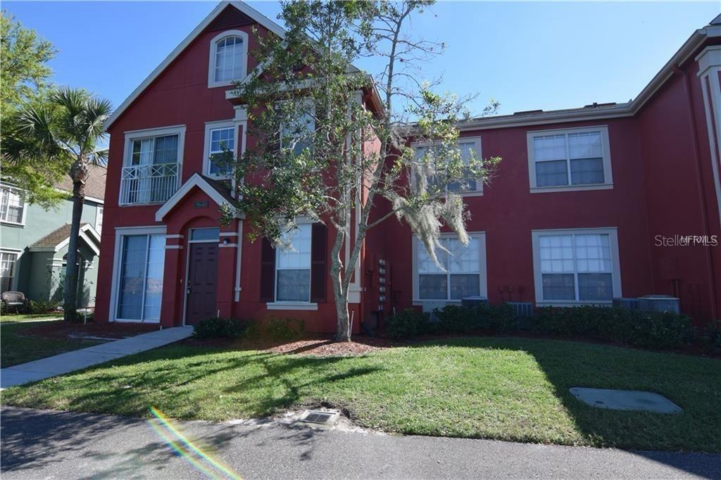 A two-story red stucco building with white trim and a front entrance — 9640 LAKE CHASE ISLAND WAY, TAMPA, FL