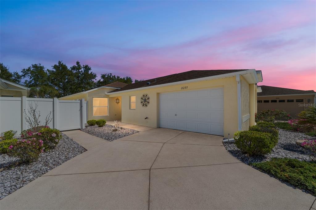 A single-story house with a yellow stucco exterior, a white garage door, and a driveway — 2055 HYDRANGEA AVENUE, THE VILLAGES, FL