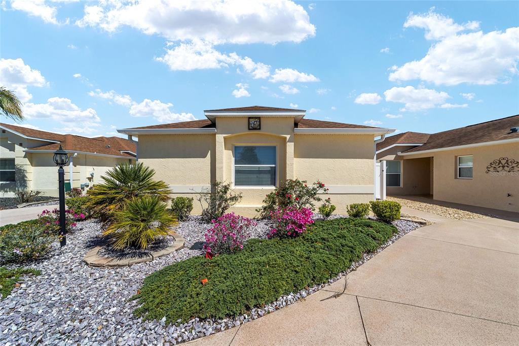 A single-story house with a beige stucco exterior, a concrete driveway, and landscaped front yard — 2055 HYDRANGEA AVENUE, THE VILLAGES, FL