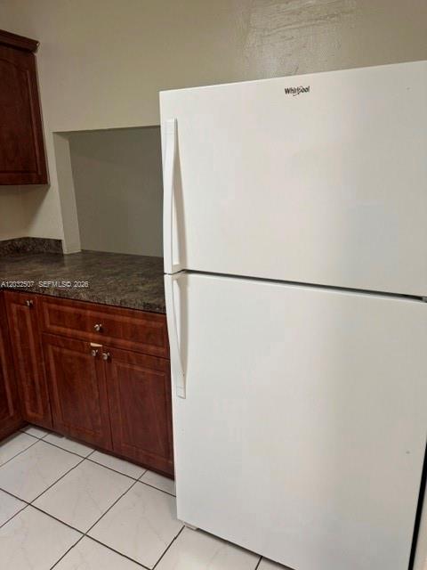 A white top-freezer refrigerator stands next to wood cabinets and a dark countertop in a kitchen — 10000 NW 80th Ct # 2249, Hialeah Gardens FL 33016, HIALEAH GARDENS, FL