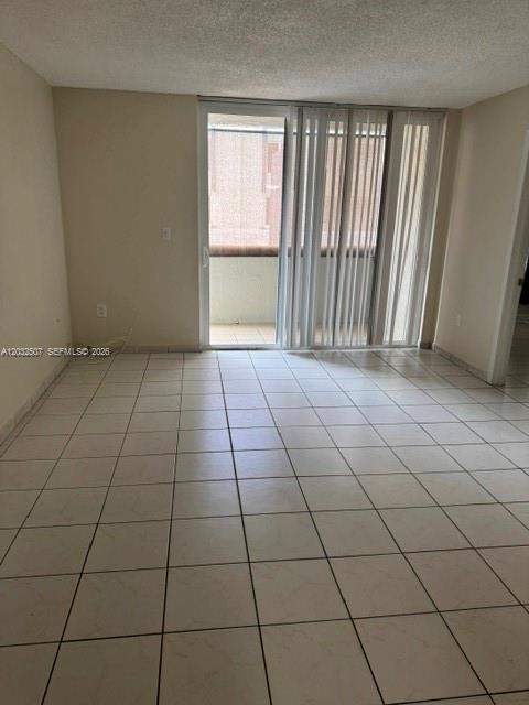 An empty room with light-colored tile flooring and a sliding glass door leading to a balcony — 10000 NW 80th Ct # 2249, Hialeah Gardens FL 33016, HIALEAH GARDENS, FL