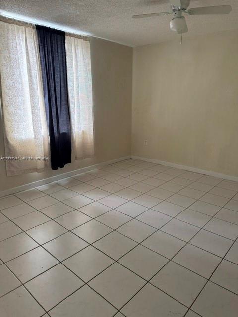 An empty room with white tiled floors, a ceiling fan, and curtains over a window — 10000 NW 80th Ct # 2249, Hialeah Gardens FL 33016, HIALEAH GARDENS, FL
