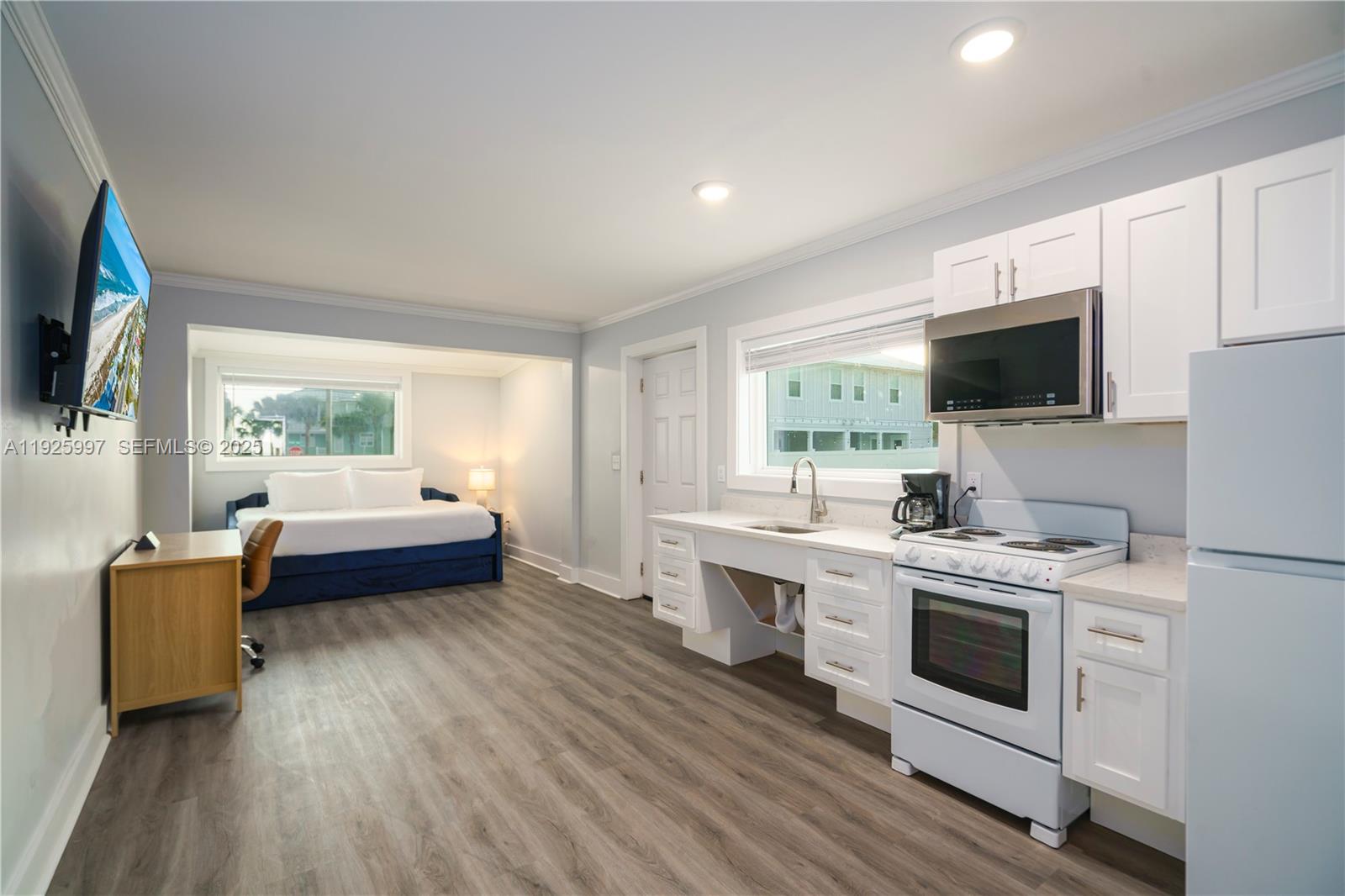 A studio apartment features a kitchen with white cabinets, a desk, and a bed area — 17784 Front Beach Rd # 16, Panama City FL 32413, PANAMA CITY, FL