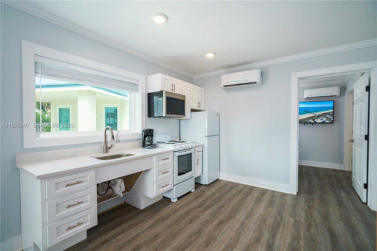 A kitchen features white cabinetry, a sink, a stove, and a refrigerator on wood flooring — 17784 Front Beach Rd # 16, Panama City FL 32413, PANAMA CITY, FL