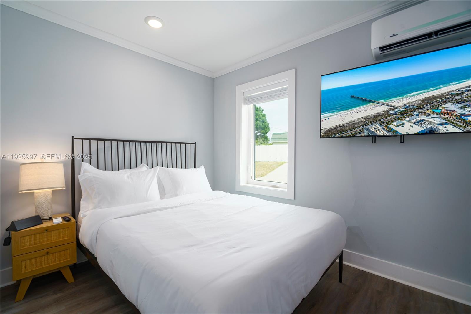 A bedroom features a bed with white bedding, a yellow nightstand, and a wall-mounted television — 17784 Front Beach Rd # 16, Panama City FL 32413, PANAMA CITY, FL