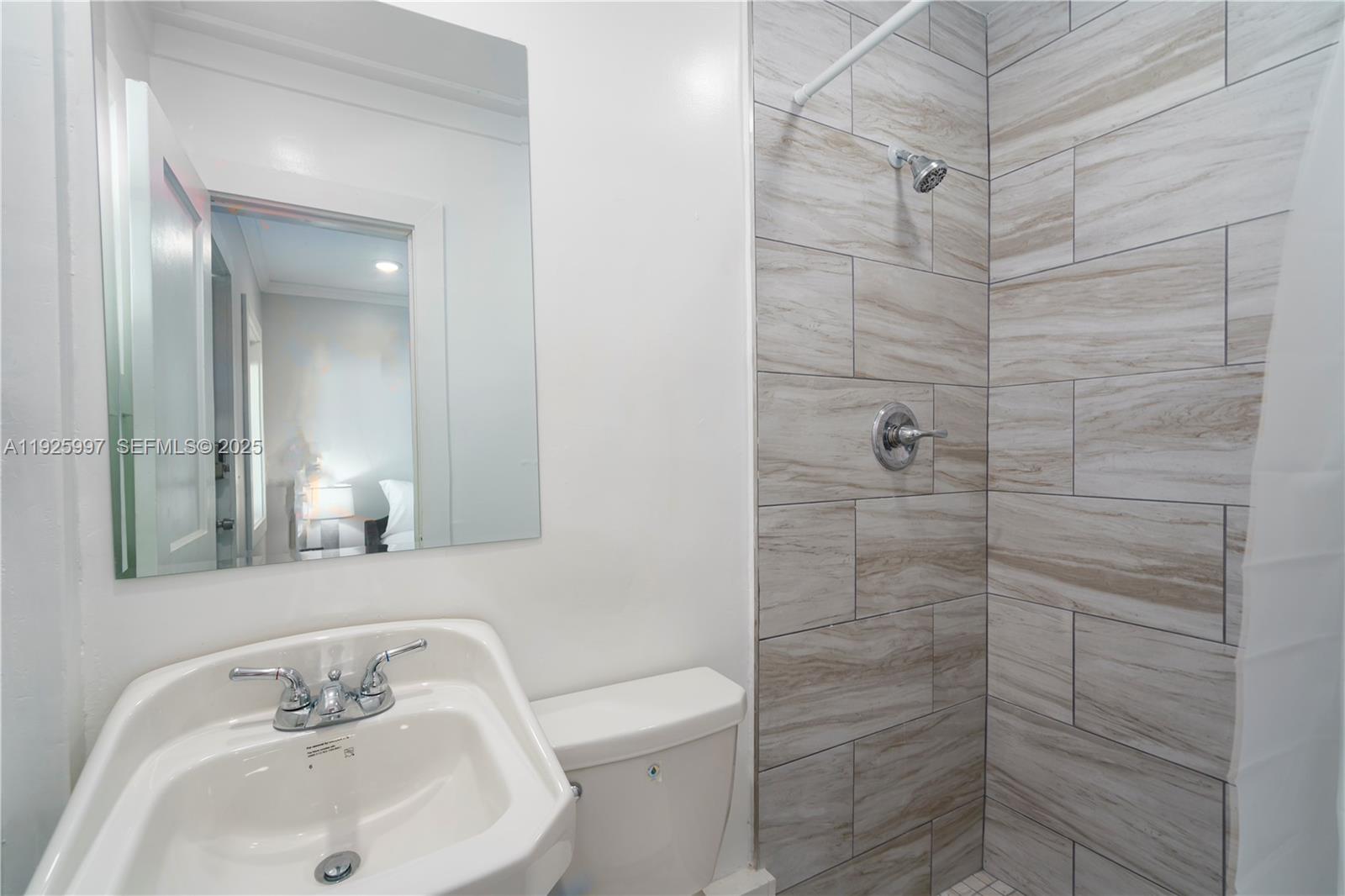 A bathroom features a pedestal sink, a toilet, and a tiled walk-in shower — 17784 Front Beach Rd # 16, Panama City FL 32413, PANAMA CITY, FL