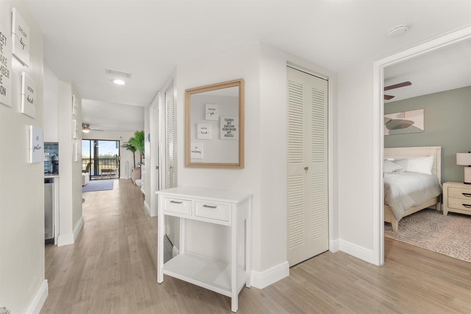 A hallway with a white console table, a mirror, and a view into a bedroom — 14500 Stirling Way # 403, Delray Beach FL 33446, DELRAY BEACH, FL