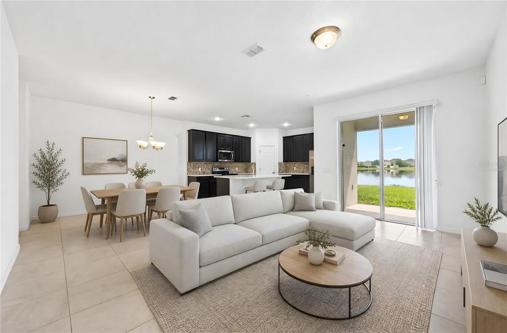 An open-concept living room and kitchen feature tile floors, dark cabinetry, and a lake view — 15523 WILLOW ARBOR CIRCLE, ORLANDO, FL