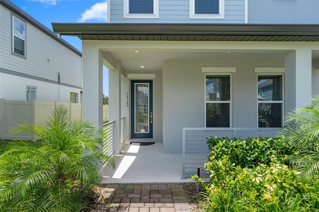 The exterior of a house features a covered porch, a blue front door, and landscaping — 14340 BRAEMAR STREET, WINTER GARDEN, FL