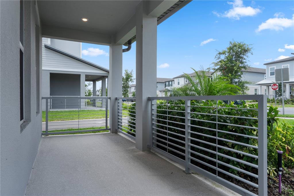 A covered concrete porch features gray metal railings and views of a suburban neighborhood — 14340 BRAEMAR STREET, WINTER GARDEN, FL