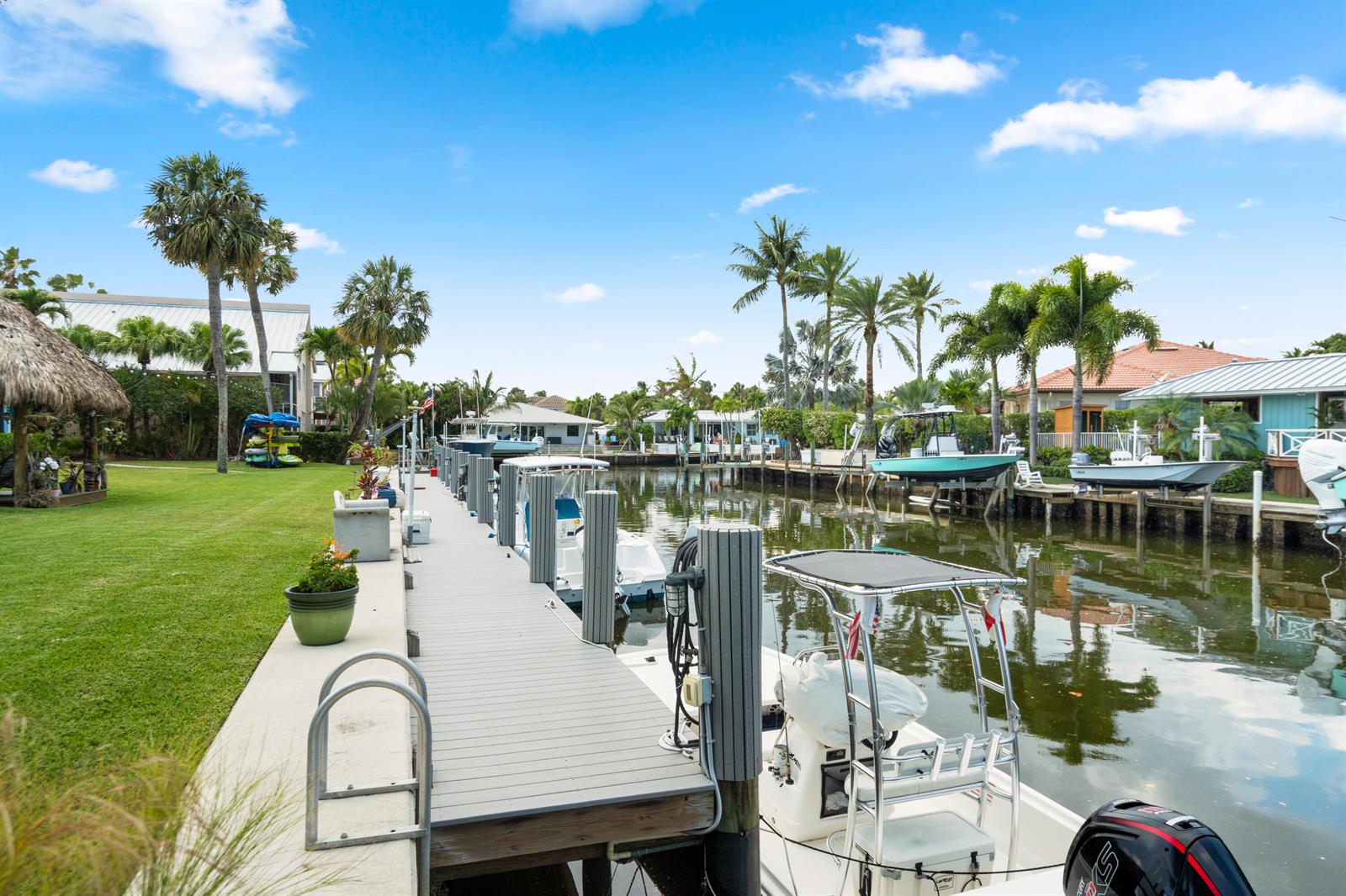 A wooden dock extends into a canal lined with boats, palm trees, and waterfront homes — 249 Center Street # 2c, Jupiter FL 33458, JUPITER, FL