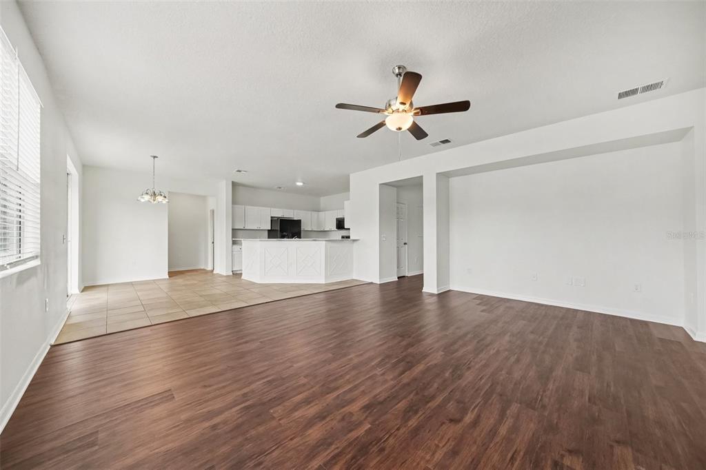 A living room with dark wood-look flooring, a ceiling fan, and stairs leading upward — 2012 BEARING LANE, KISSIMMEE, FL