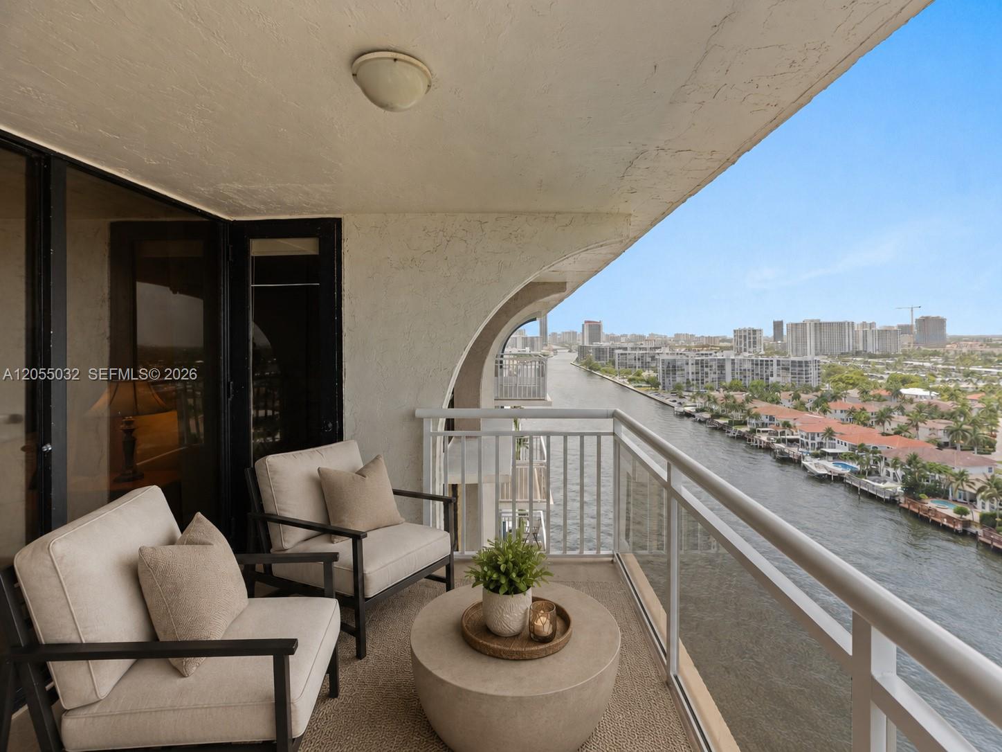 A balcony with two chairs and a table overlooks a canal and city skyline — 1600 S Ocean Dr # 18B, Hollywood FL 33019, HOLLYWOOD, FL