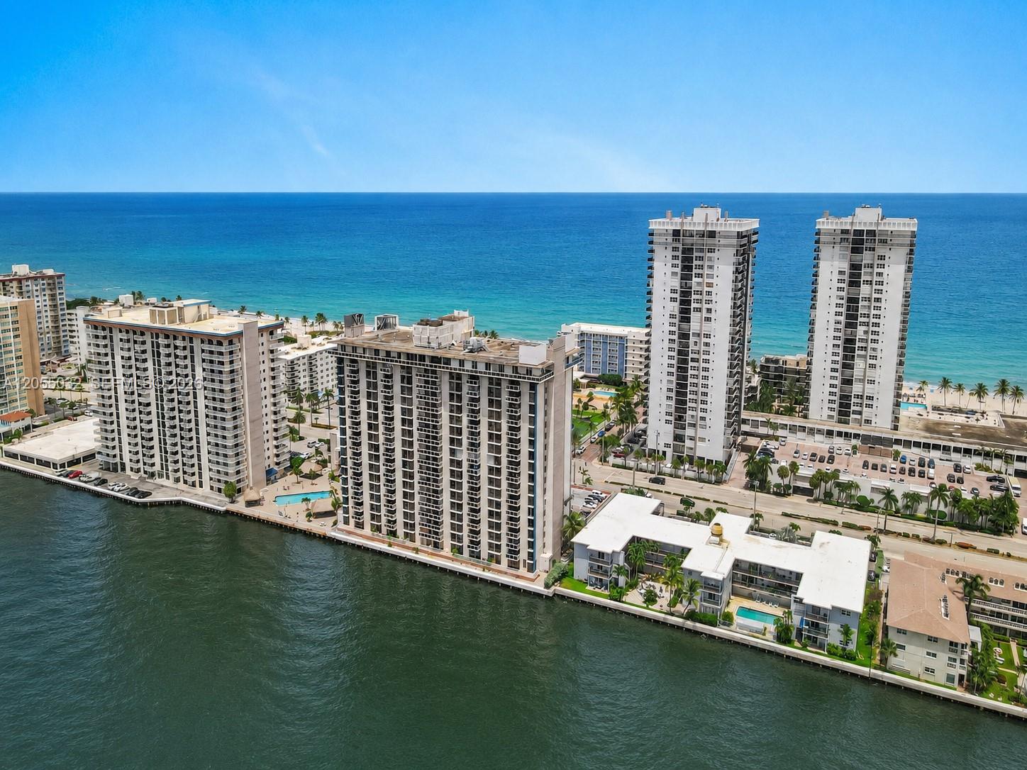 An aerial view shows several high-rise apartment buildings situated along a waterfront and oceanfront — 1600 S Ocean Dr # 18B, Hollywood FL 33019, HOLLYWOOD, FL