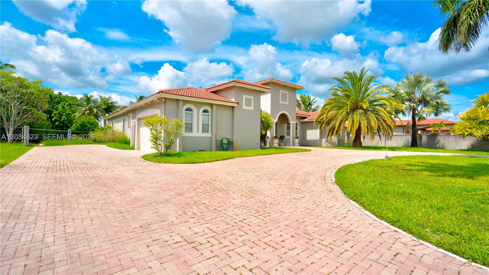 A beige house with a red tile roof and a large brick-paved driveway — 9810 NW 137th St, Hialeah Gardens FL 33018, HIALEAH GARDENS, FL